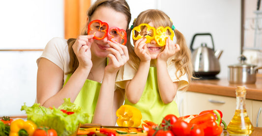 Mother and daughter playing with vegetables while cooking.